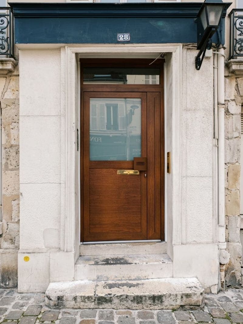 Porte d’entrée en bois sur mesure dans une façade en pierre à Paris